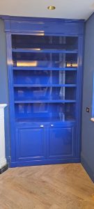 Librería a medida lacada en azul con estantes y armarios inferiores