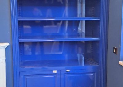 Librería a medida lacada en azul con estantes y armarios inferiores