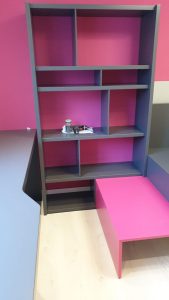 Librería a medida juvenil con estanterías en color gris y rosa