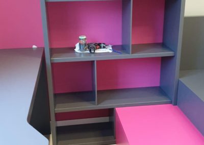 Librería a medida juvenil con estanterías en color gris y rosa