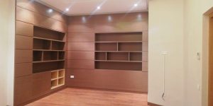 Librería empotrada a medida en salón con estantes abiertos y módulos cerrados