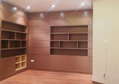 Librería empotrada a medida en salón con estantes abiertos y módulos cerrados