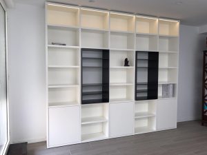 Librería a medida blanca con estanterías abiertas y módulos cerrados diseñada en Madrid