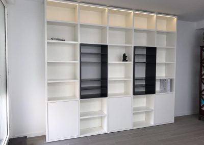 Librería a medida blanca con estanterías abiertas y módulos cerrados diseñada en Madrid